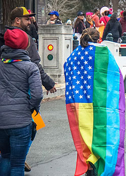 LGBTQ supporter wears a rainbow striped American flag at the Women's March in Washington, D.C. 2017.