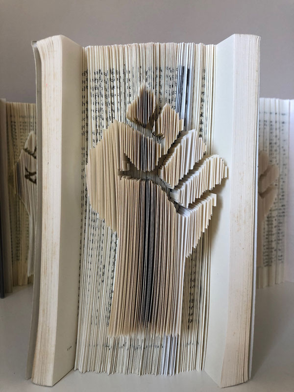 raised fist sculpted into the fore edge of a book by cutting and folding pages