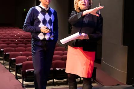 A woman instructing a young man on a stage