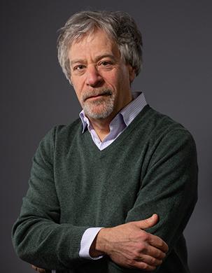 A man with gray hair in a green sweater
