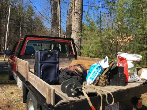 pickup truck with items in the back, including heavy bags of pellets, a backpack, and elastic bands