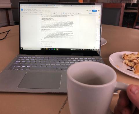 A cup of tea, the remains of breakfast, and a laptop mid-homework