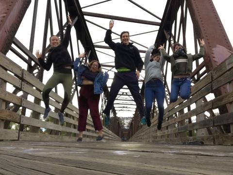 Five of us are jumping in mid air and laughing on the bridge that crosses Connecticut River