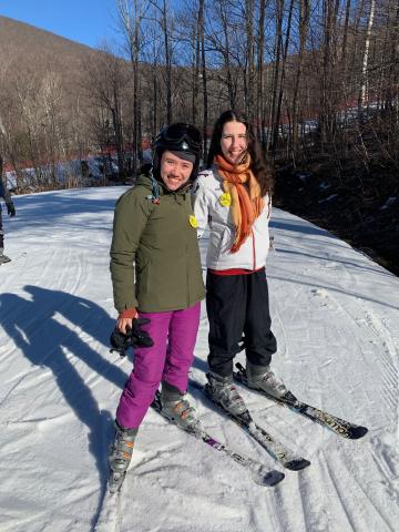 I stand next to a friend on a ski slope, smiling at the camera.