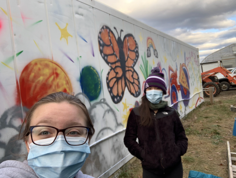 My friend and I stand near a storage container at the farm that we helped spray paint