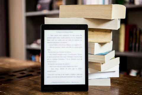 a kindle propped up against a stack of books