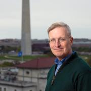 A man standing in front of the Washington Monument in the distance