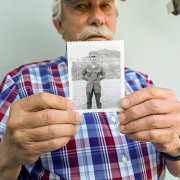 A older man holding up a black and white photo
